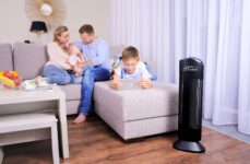 Čistička vzduchu Ionic-CARE v obývacej izbe, rodina relaxuje na svetlej pohovke pri okne v pozadí, farba čierna
