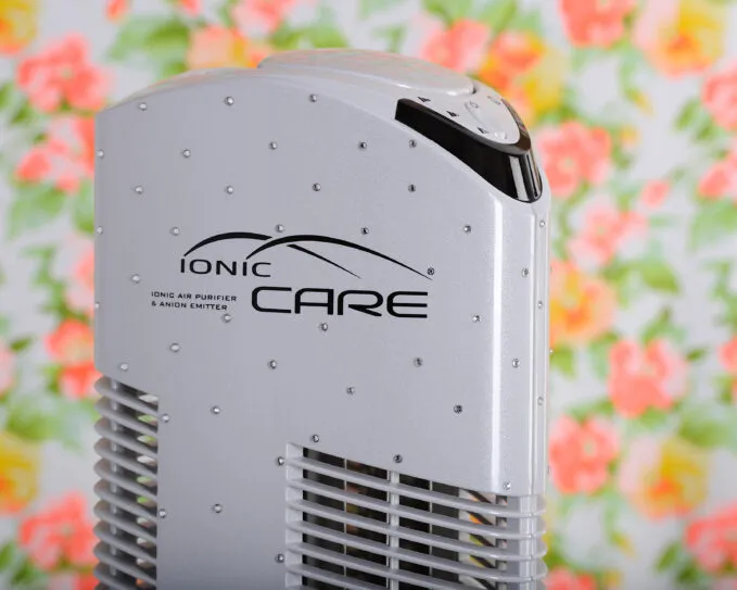 Čistička vzduchu Ionic-CARE v interiéri s farebným kvetinovým pozadím, biela farba s kryštálmi