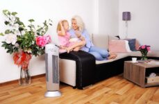 Čistička vzduchu Ionic-CARE v obývačke vedľa pohovky, na ktorej relaxuje malá mamička s dcérkou, farba strieborná