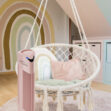 Ružová čistička vzduchu Ionic-CARE v detskej izbe pri hojdacom kresle, dúhový obraz v pozadí