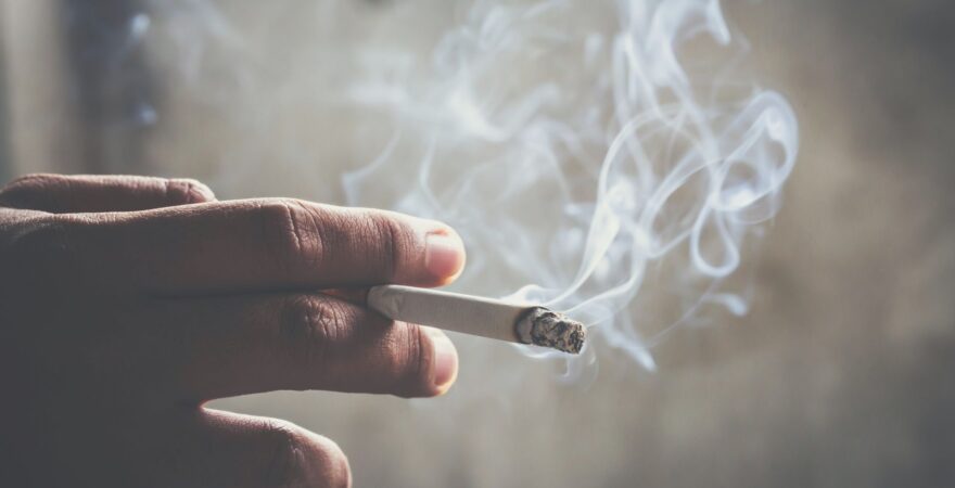 Zapálená dymiaca cigareta v ruke.
